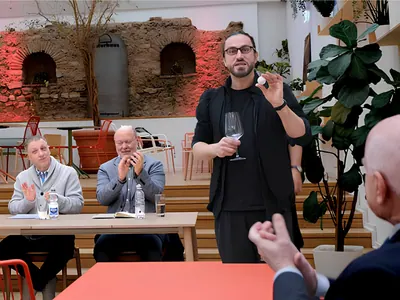 Christoph Demian bei einer Kartenvorführung vor einer Vierergruppe mit Glas in der Hand